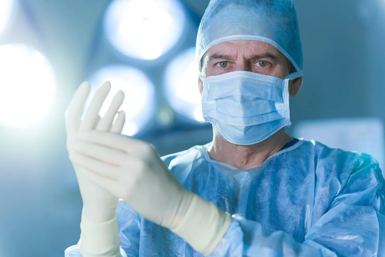concentrated surgeon is wearing gloves and looking at camera with determination portrait