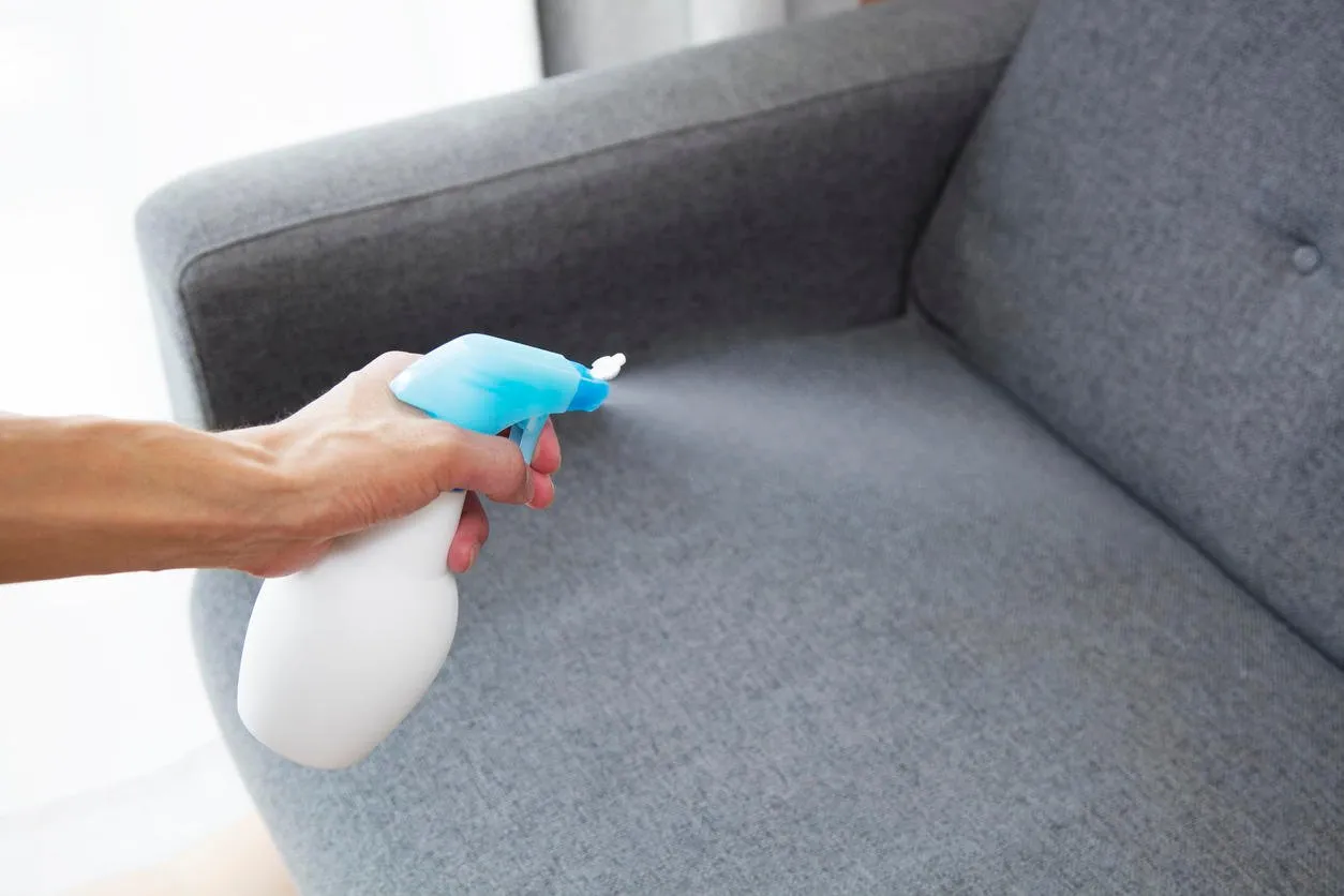 sprayed air freshener in hand on home interior background