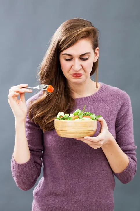 jeune fille mécontente étant difficile à manger salade verte mélangée avec des tomates cerises comme régime végétarien