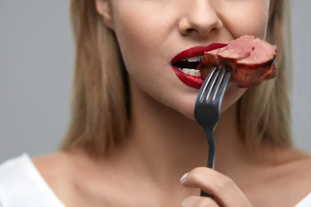woman eating meat closeup of healthy hungry girl with beautiful face, red lips eats delicious grilled meat female mouth biting piece of tasty beef steak on fork nutrition concept high resolution
