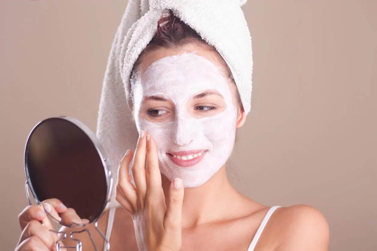 jeune fille appliquant un masque sur son visage et regardant dans le miroir
