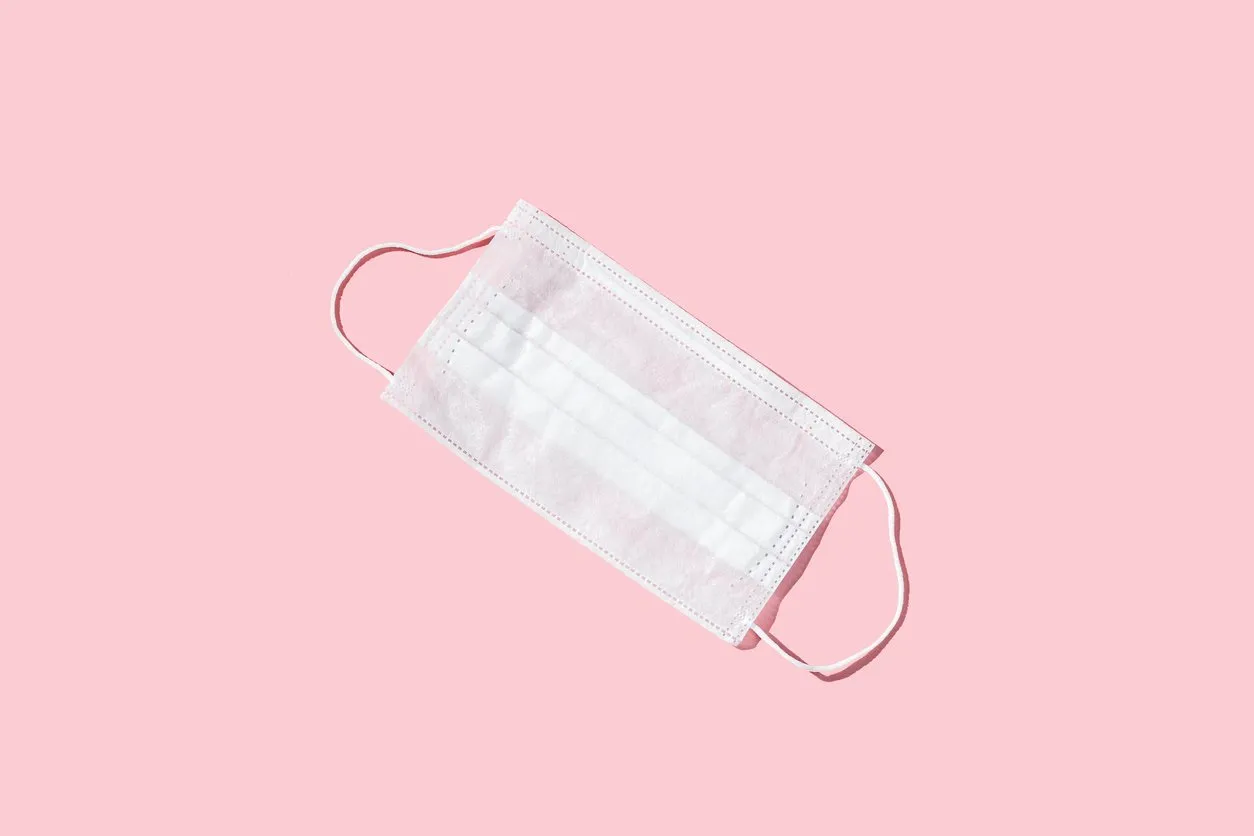 medical mask on the pink colored table epidmic concept mask to cover the mouth and nose for protection from virus and bacteria flat lay