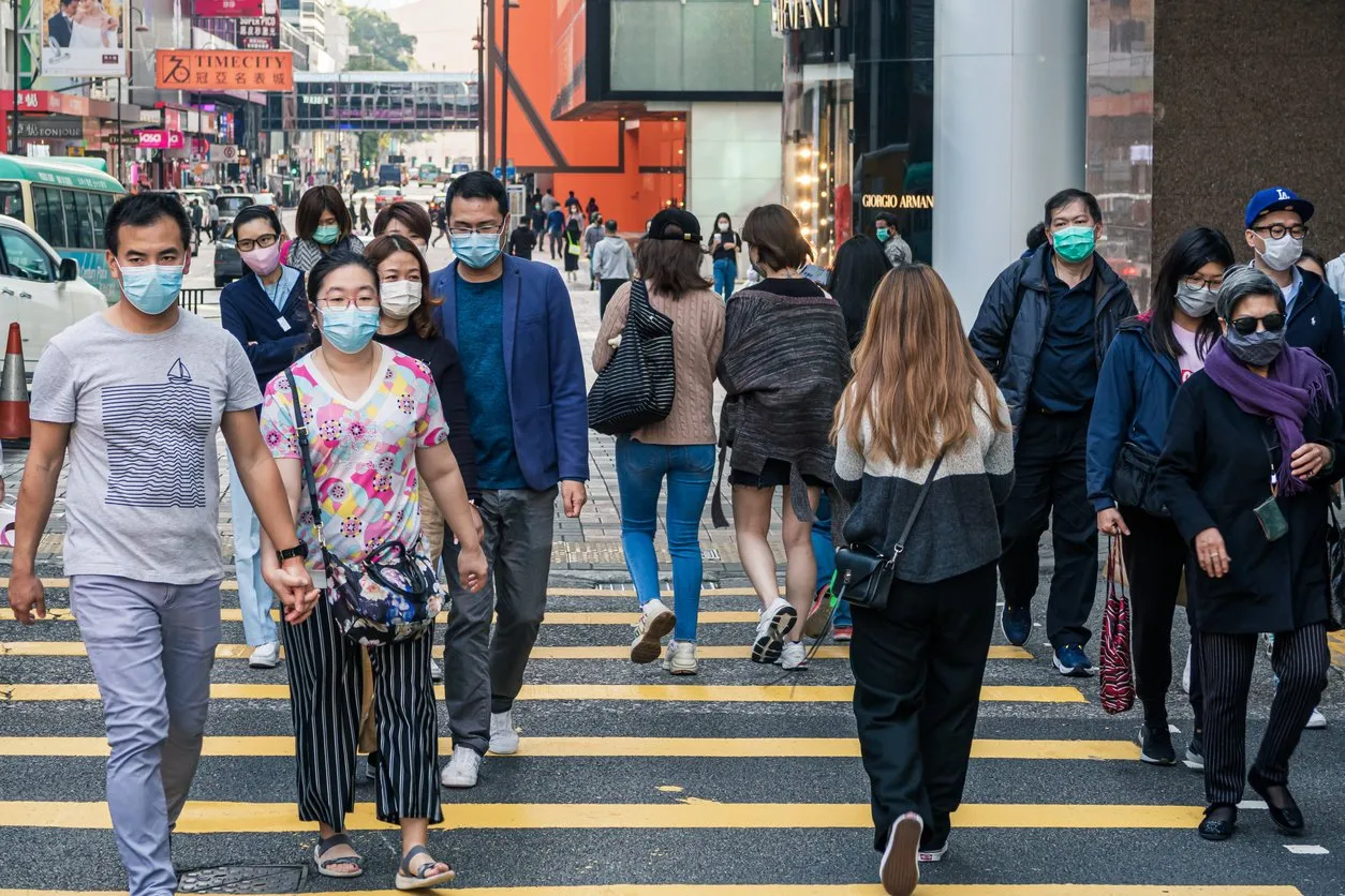 tsim sha tsui, hong kong - 22 february, 2020   people walking across nathan road kowloon, hong kong citizens fearing coronavirus wear masks on the street