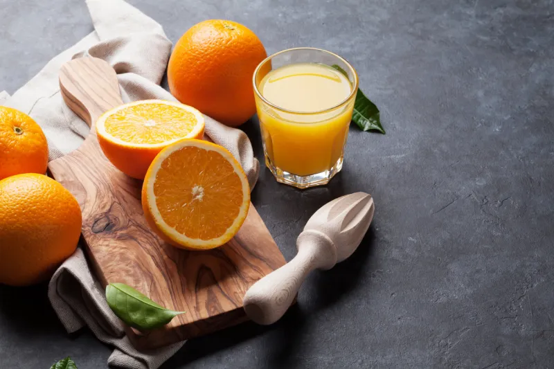 fresh orange fruits and juice on stone table view with copy space