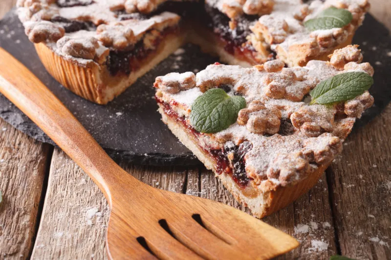 piece of cake with plum jam and powdered sugar close-up on the table horizontal
