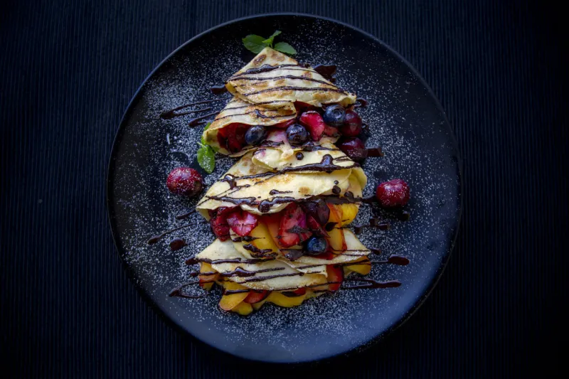 crepes with fresh berries, chocolate sauce and powdered sugar