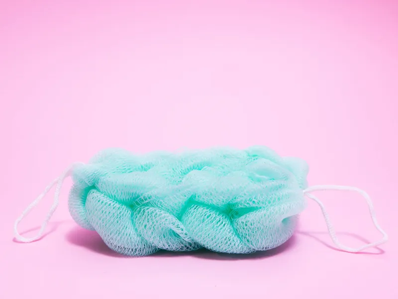close-up of vivid turquoise blue fluffy sponge on pink background