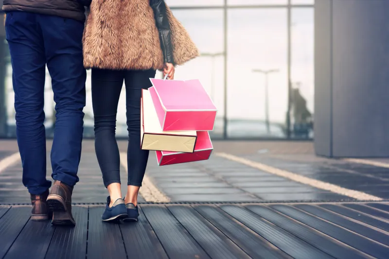 midsection of couple with shopping bags in city