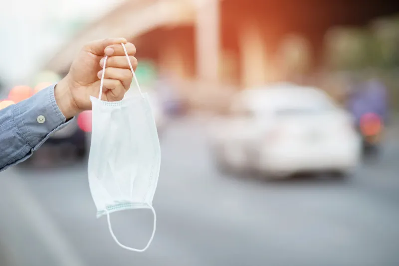 close up hand holding submit wearing facial hygienic mask nose outdoor ecology, air pollution car, environmental and virus protection concept flu health against toxic dust the city of a health effect