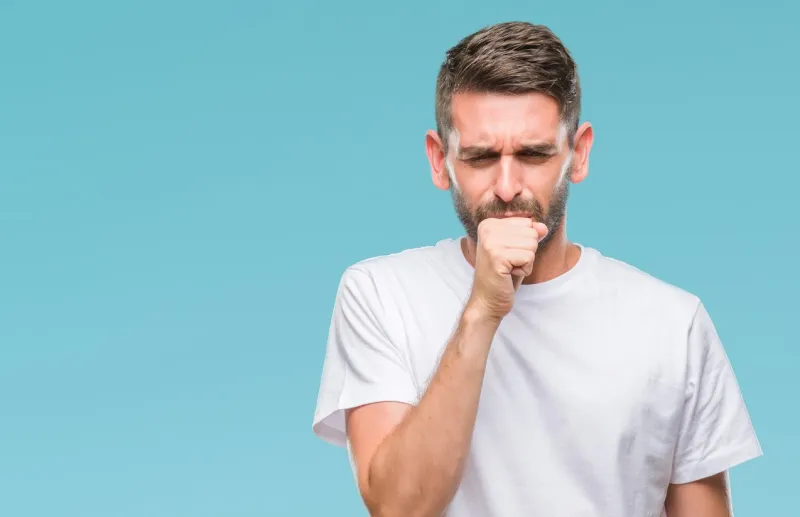 young handsome man over isolated background feeling unwell and coughing as symptom for cold or bronchitis healthcare concept