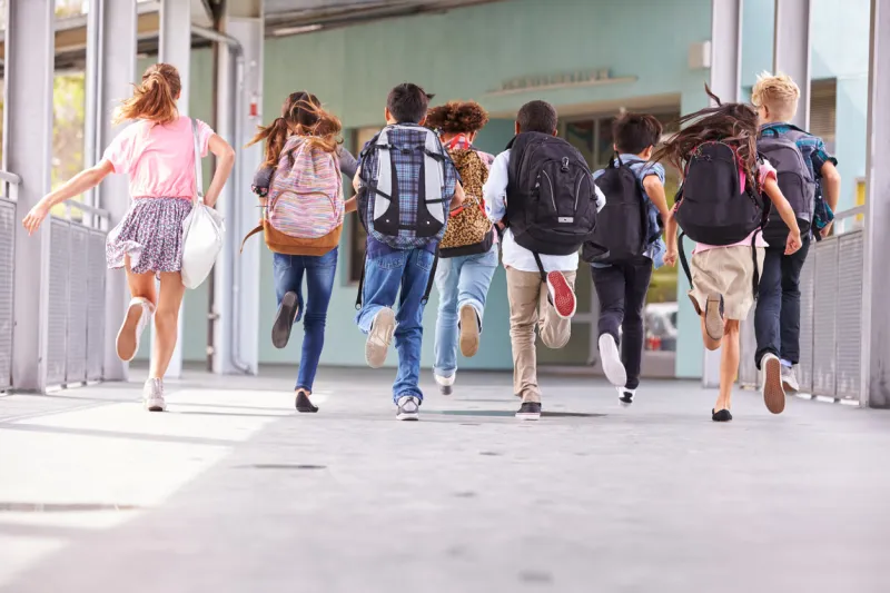 group of elementary school kids running at school, back view