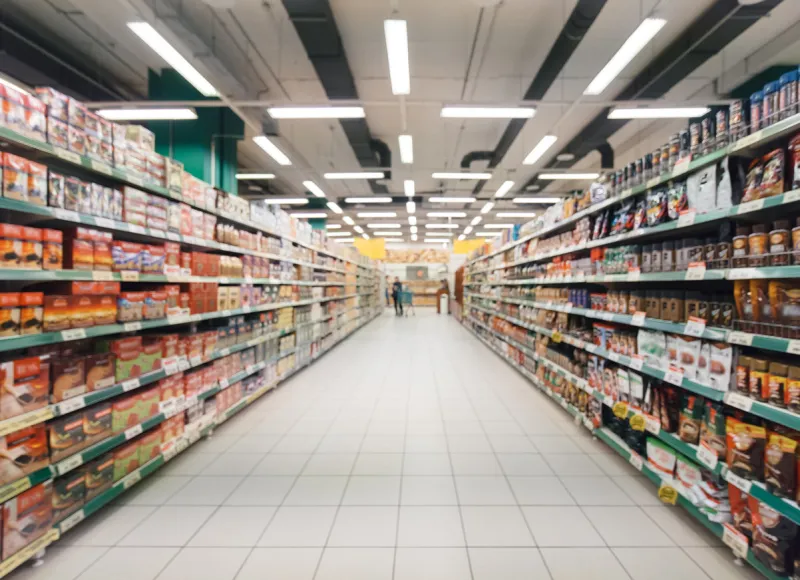 abstract blurred supermarket aisle with colorful shelves and unrecognizable customers as background