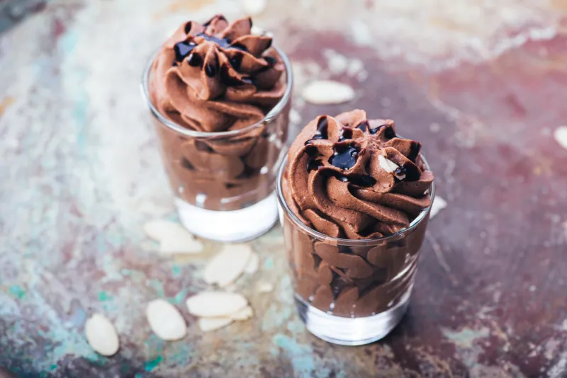 chocolate mousse with chocolate sauce and chocolate pieces, almond slices in a glasses on a vintage background