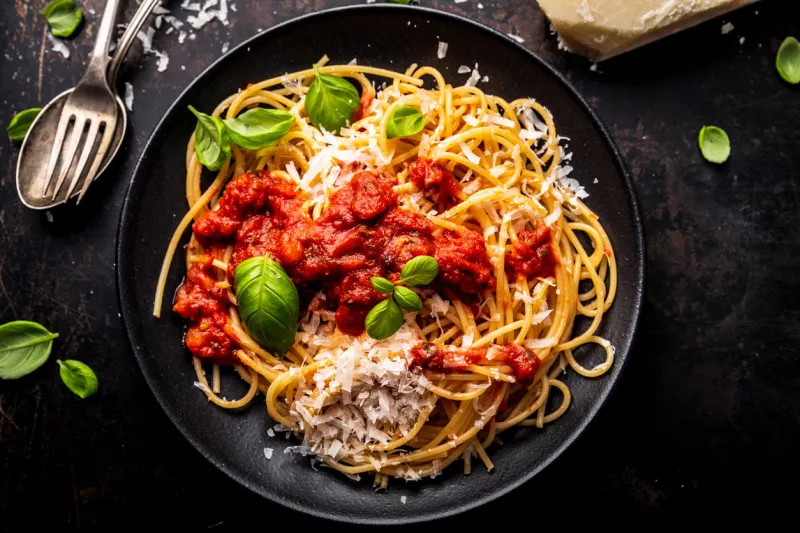 delicious appetizing classic spaghetti pasta with tomato sauce, parmesan cheese and fresh basil, top view
