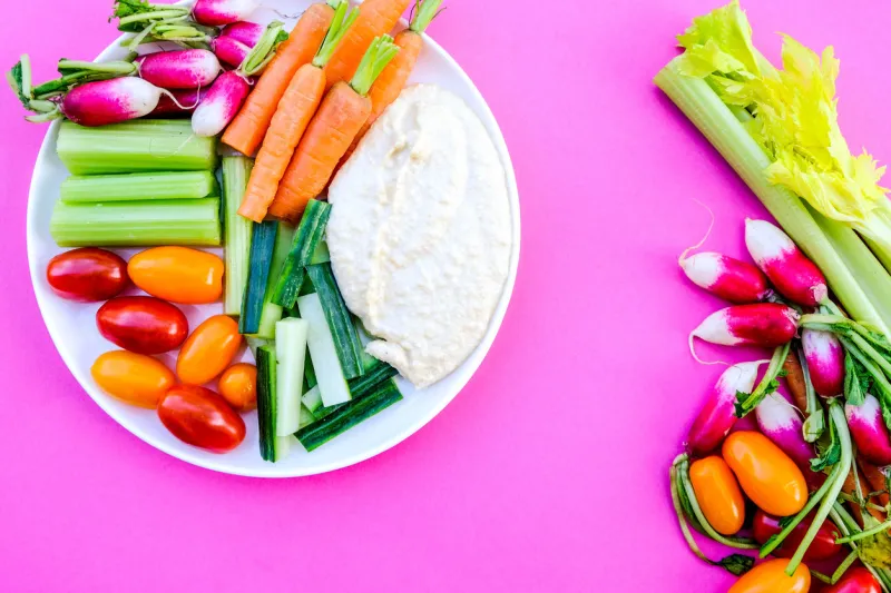 fresh vegetable crudite platter with hummus and baby carrots, radishes, cucumber, celery and tomatoes