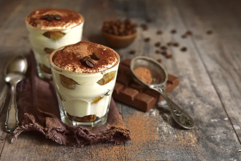 homemade traditional italian dessert tiramisu with mascarpone cheese,savoyardi biscuit,coffee and whipped cream in a glasses over dark wooden background