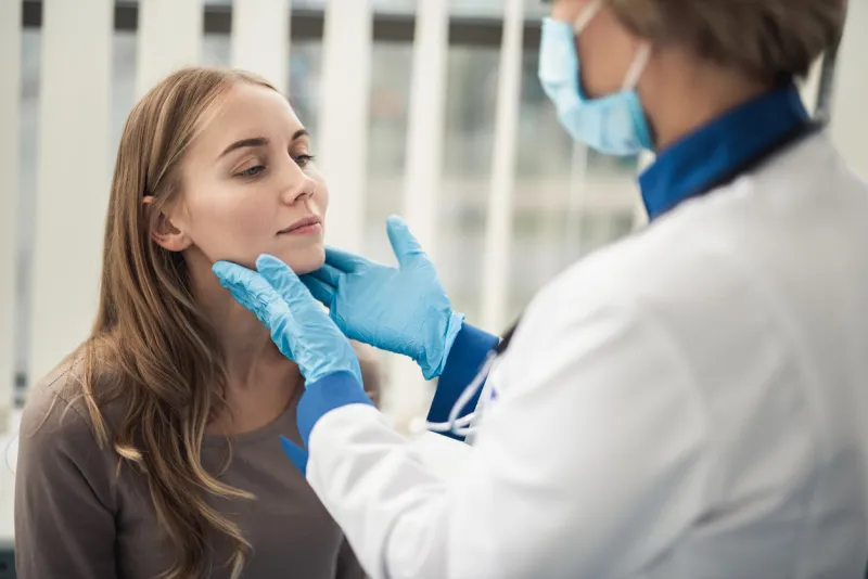 concept of professional consultation in therapist system close up portrait of doctor woman examining tonsils of smiling young lady in medical office