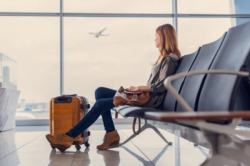start of her journey beautiful young woman looking out window at flying airplane while waiting boarding on aircraft in airport lounge