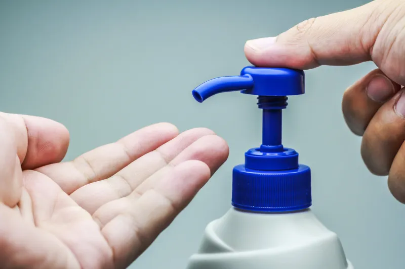 male hand and pumping bottle on white background