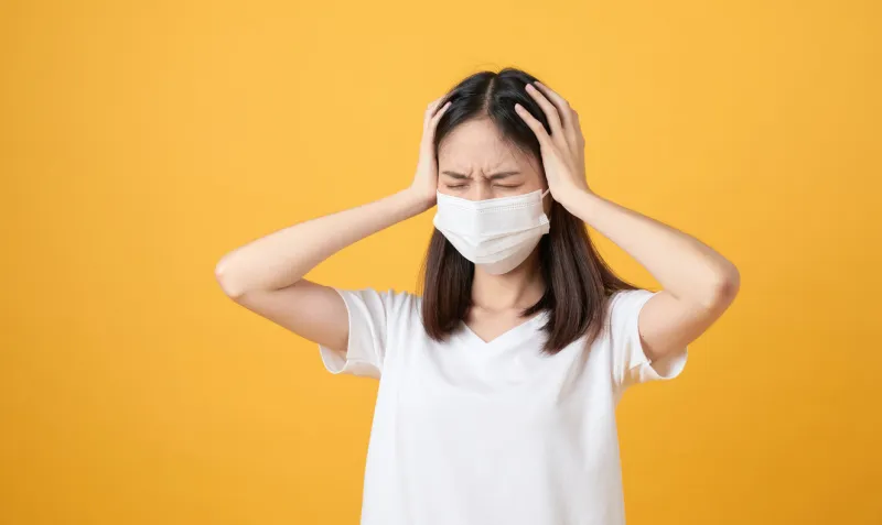 asian women wear masks to protect disease and the headache from a virus on orange background