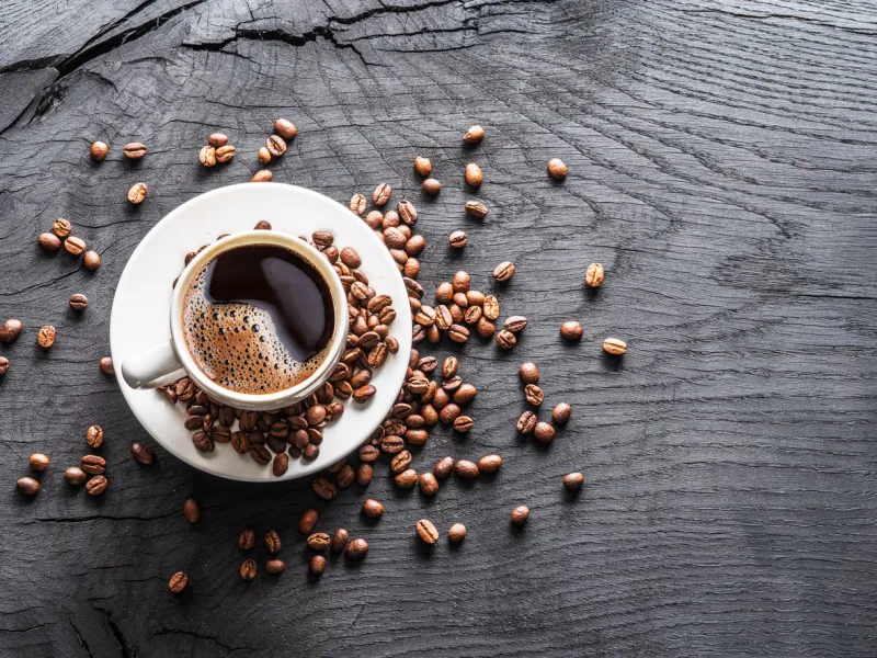 cup of coffee surrounded by coffee beans top view