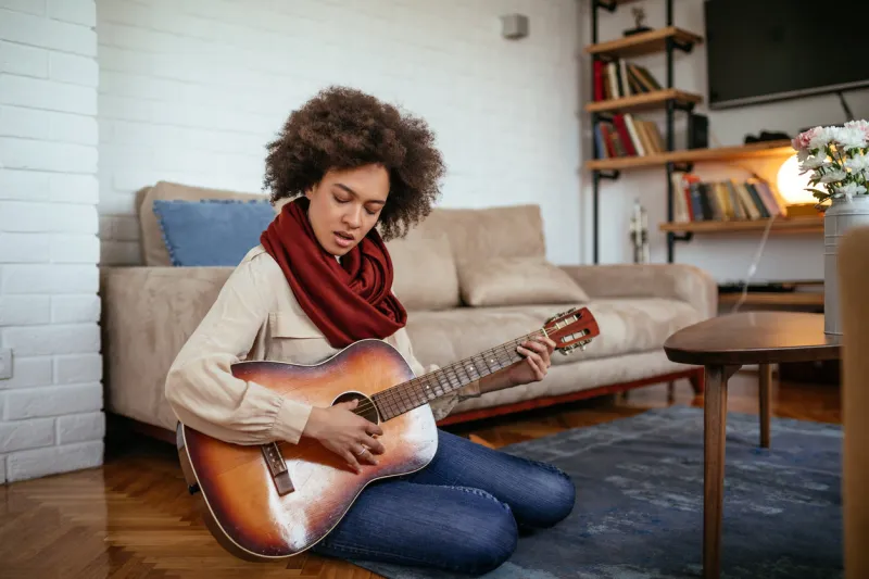 beautiful girl playing a guitar at home