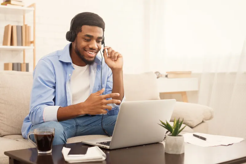 smiling african-american guy in headphones studying foreign language online through video conference application, copy space