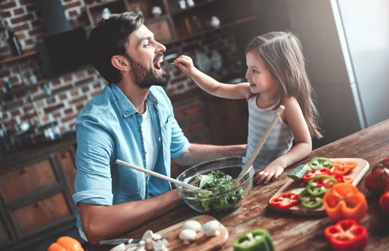 handsome man and his little cute daughter are cooking on kitchen making salad healthy lifestyle concept
