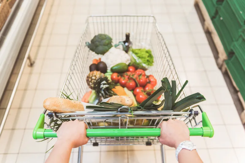top view close up woman hands pulling full shopping grocery cart in modern shop