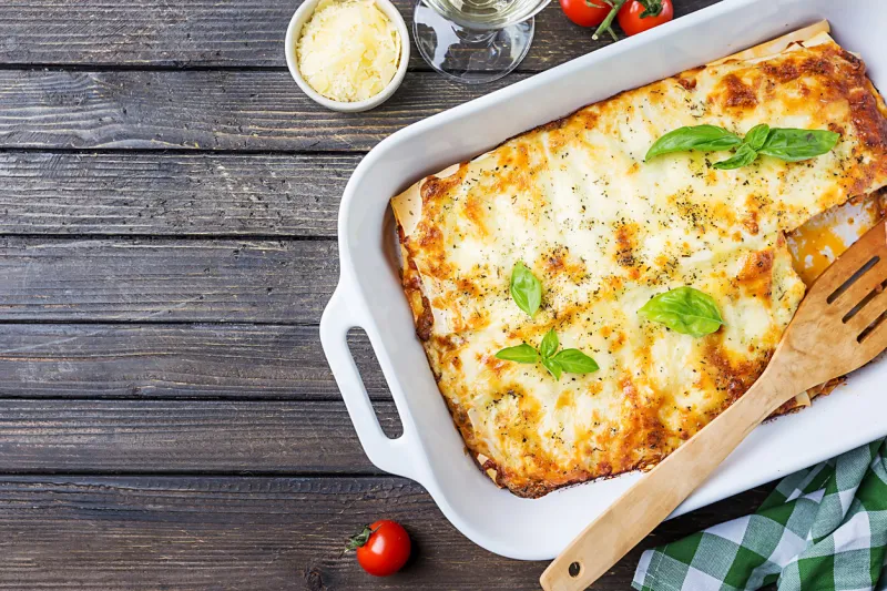 traditional italian lasagna with vegetables, minced meat and cheese on a wooden background top view, copy space