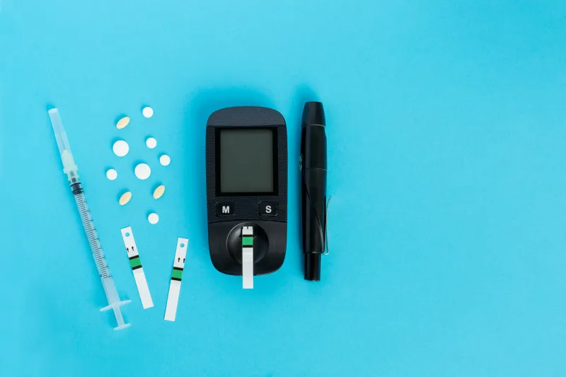 glucometer, medication, syringe lie on a blue background