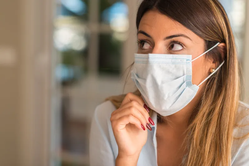 beautiful young woman wearing contamination mask at home pollution and illness concept