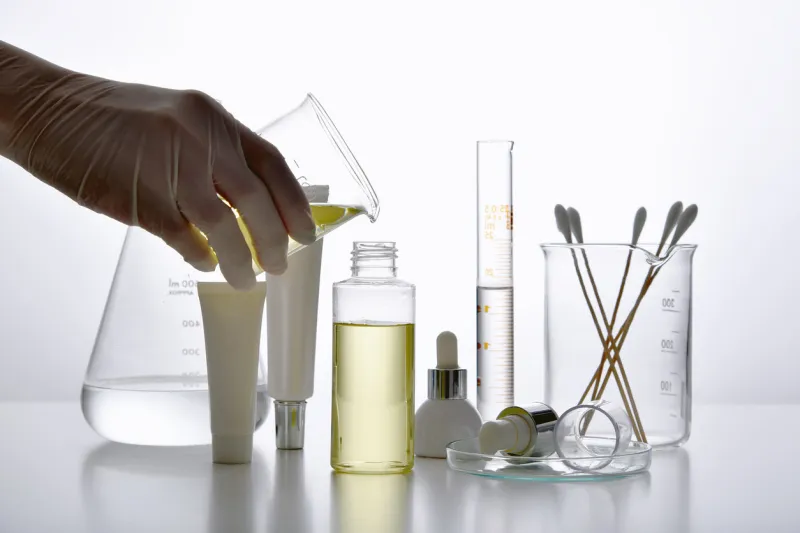 dermatologist formulating and mixing pharmaceutical skincare, cosmetic bottle containers and scientific glassware, research and develop beauty product concept