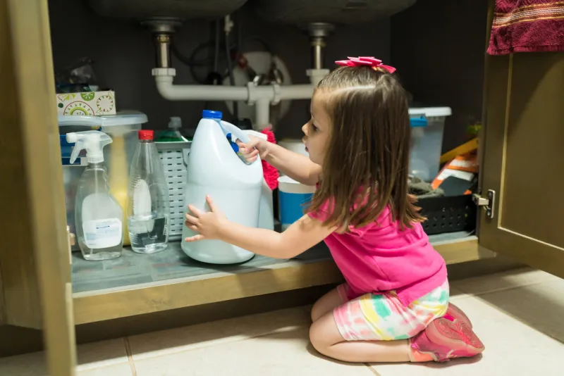 little kid removing container from cabinet in kitchen at home