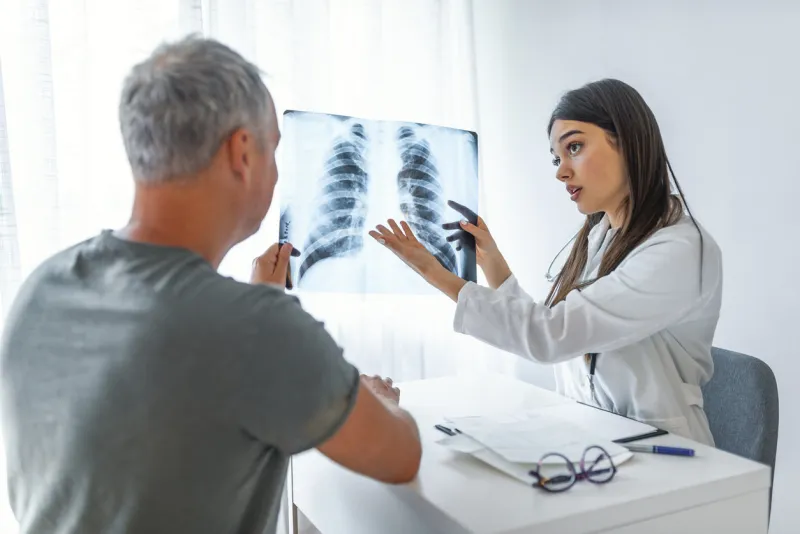 young doctor talking to a patient in her cabin doctor showing x-ray to patient doctor and patient looking at xray in medical office doctor shows the patient chest x-ray