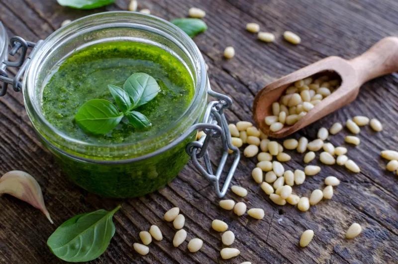 pesto genovese - traditional italian green basil sauce with pine nuts, basil and garlic on rustic wooden background