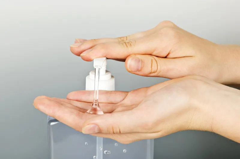 female hands using hand sanitizer gel pump dispenser
