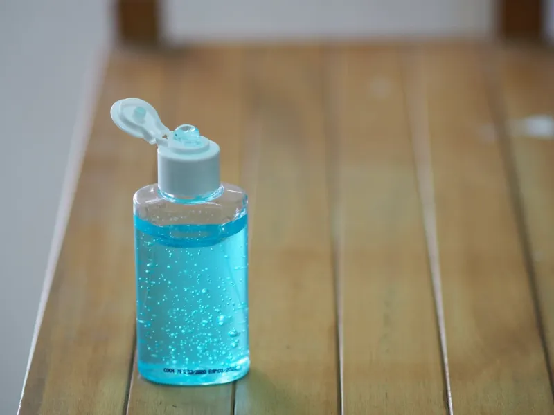 hand wash gel in plastic bottle on wooden desk, to prevent germs protect virus covid