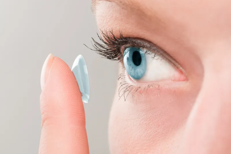 woman inserting a contact lens in her eye