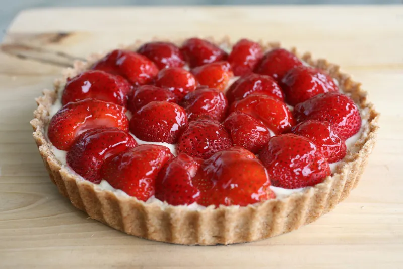 close-up of a homemade strawberry tart with jam glazing against a wood background taken by a canon 5d