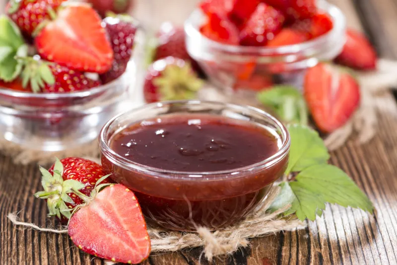 bowl with strawberry sauce on vintage wooden background
