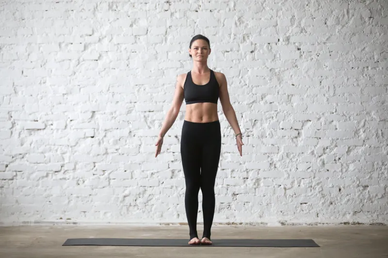 middle aged yogi attractive smiling woman practicing yoga concept, standing in mountain exercise, tadasana pose, working out, wearing black sportswear top and pants, full length, white loft background