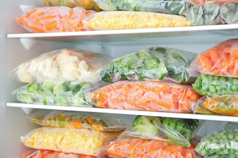 plastic bags with deep frozen vegetables in refrigerator