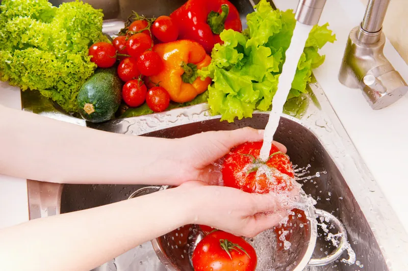 fresh vegetables under water stream in colander