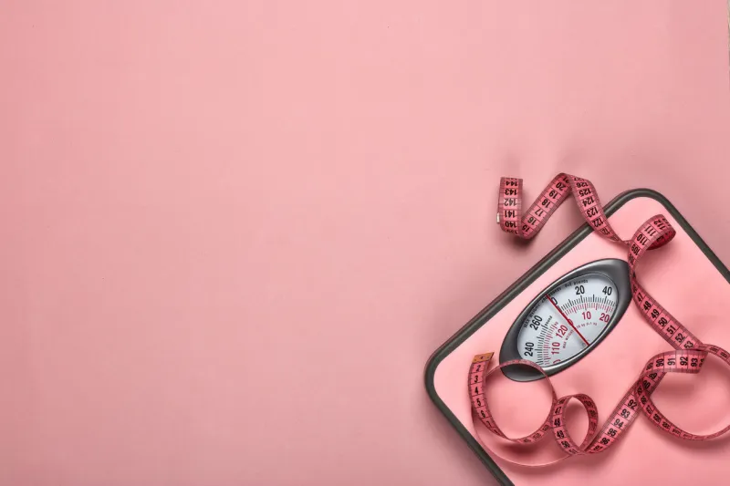 female fitness still life scales and measuring tape on pink background mockup planning of diet and trainings top view with copy space healthy lifestyle concept slimming