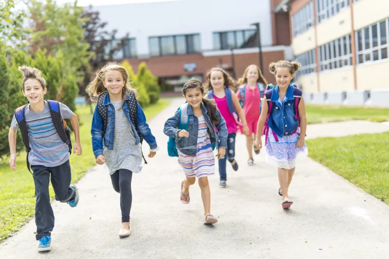 the great portrait of school pupil outside classroom carrying bags