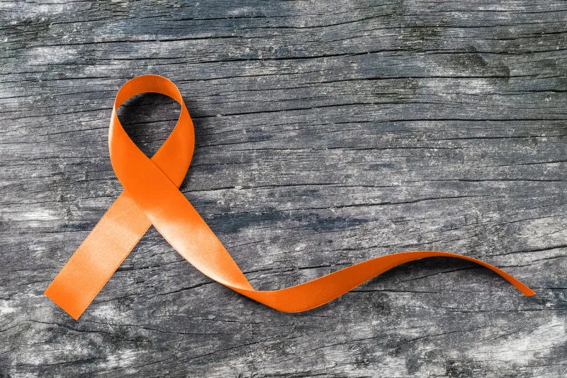 orange ribbon on old aged background raising awareness on leukemia, kidney cancer and multiple sclerosis