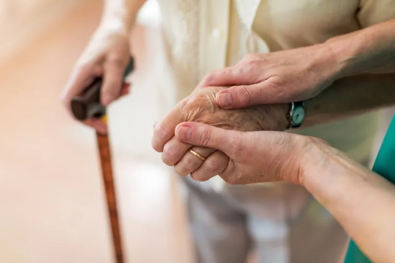 nurse consoling her elderly patient by holding her hands