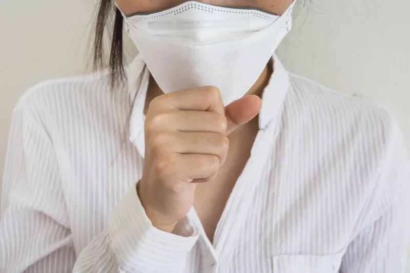 a woman wearing a mask is doing a sore throat, sick concept