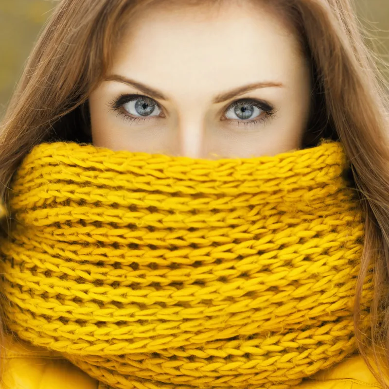 pretty woman in a yellow knit scarf looking at the camera beautiful eyes peering